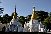 Myanmar - Inwa, white washed stupas with a Buddha statue protected by a naga where the road branch off to the teack monastery. 